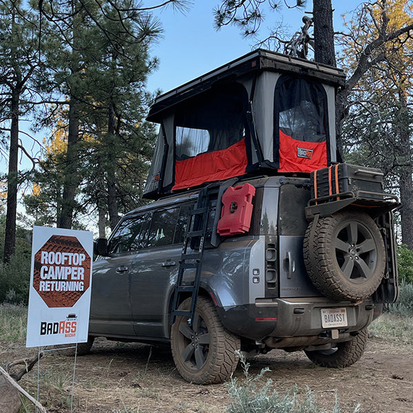 Badass Tents "CONVOY" 2020-23 Land Rover NEW Defender 110 Rooftop Tent PRE-ASSEMBLED. Rear view of open tent on vehicle at campsite 