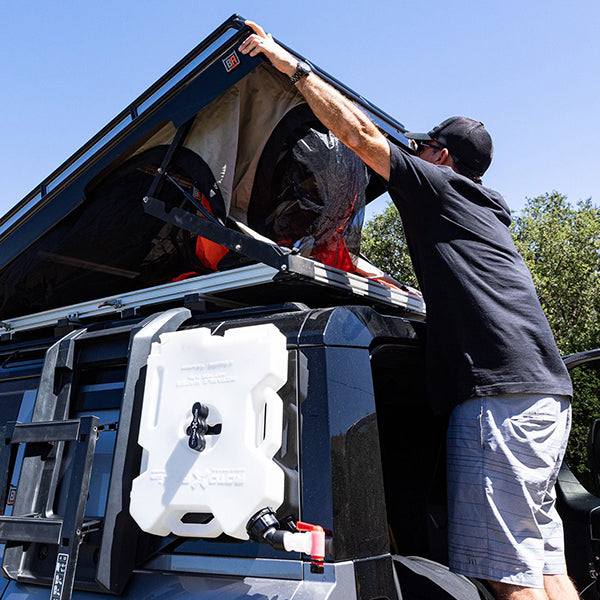 Badass Tents "CONVOY" 2020-23 Land Rover NEW Defender 110 Rooftop Tent PRE-ASSEMBLED. Person opening tent on vehicle outside