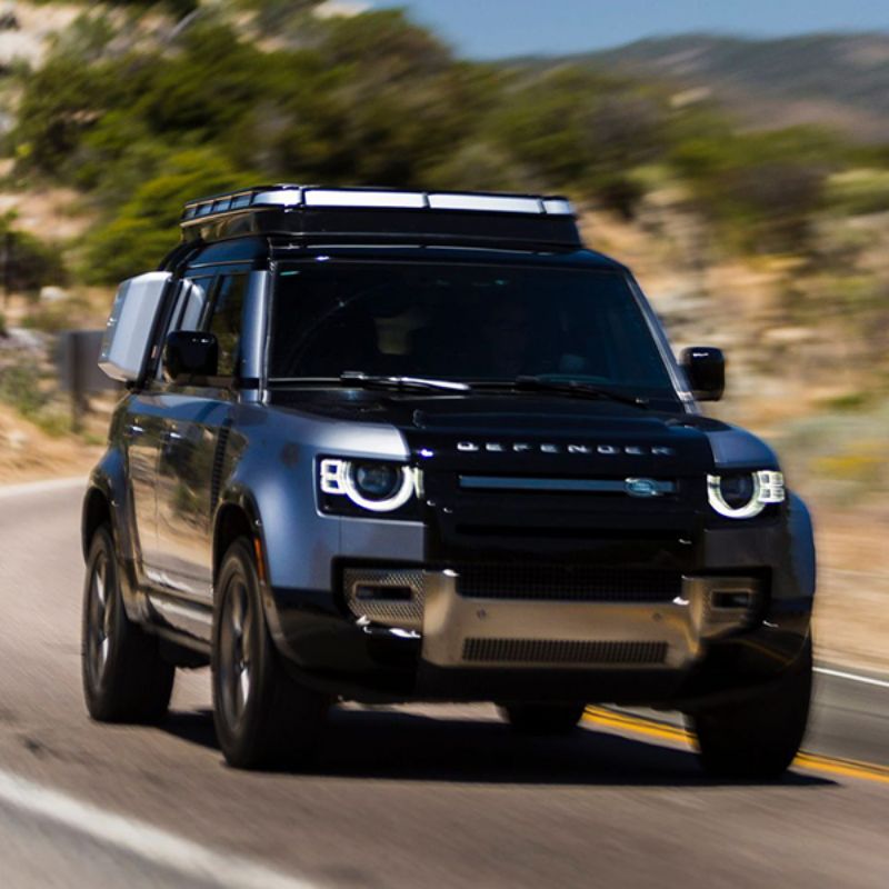 Badass Tents "CONVOY" 2020-23 Land Rover NEW Defender 110 Rooftop Tent PRE-ASSEMBLED. Front view of closed tent on vehicle driving on road