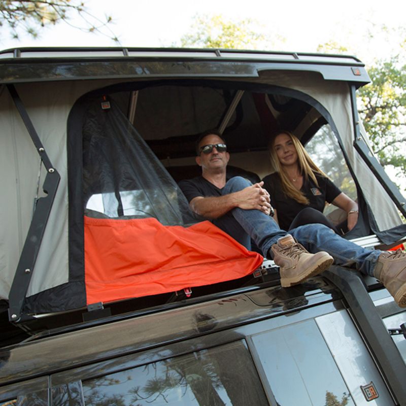 Badass Tents "CONVOY" 2020-23 Land Rover NEW Defender 110 Rooftop Tent PRE-ASSEMBLED. People sitting in open tent on vehicle