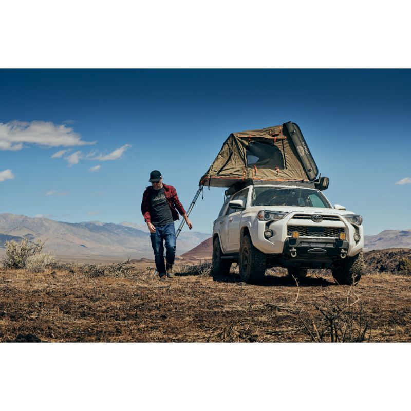 Tuff Stuff Overland Alpha II Hard Shell Rooftop Side Open Tent (2 Person).Front view of open tent on vehicle with ladder and man walking