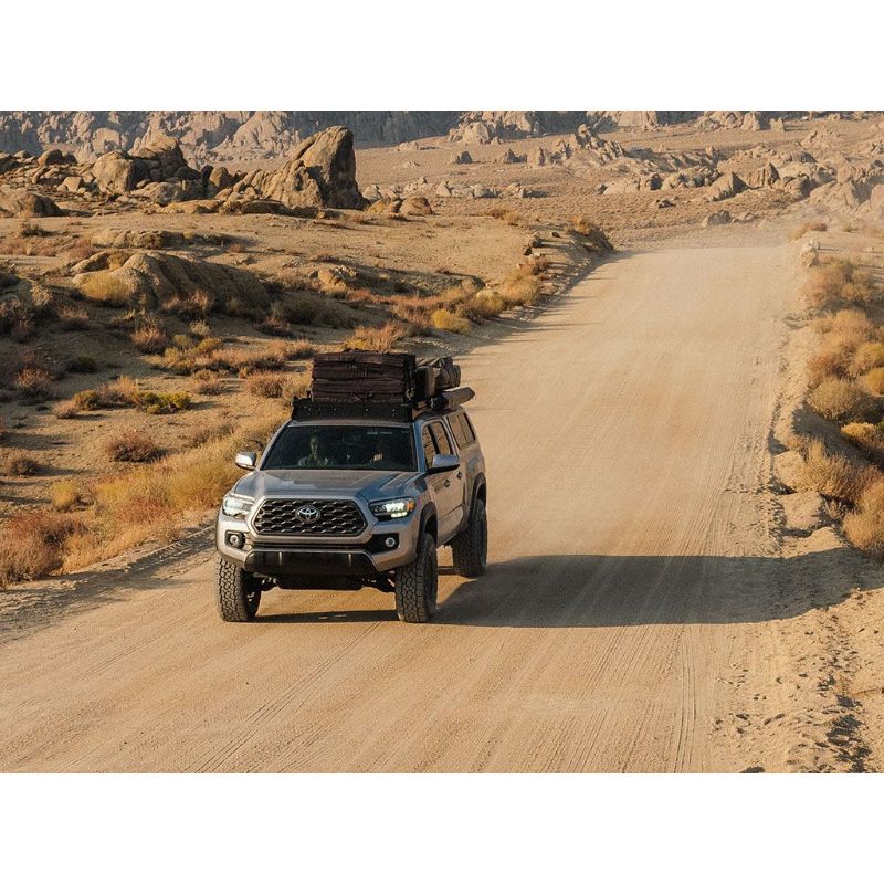 Front Runner Toyota Tacoma (2005-Current) Slimline II Roof Rack Kit. Roof rack carrying gear on vehicle driving on dirt road