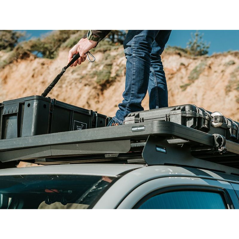 Front Runner Toyota Tacoma (2005-Current) Slimline II Roof Rack Kit.Person standing on roof rack on vehicle attaching gear