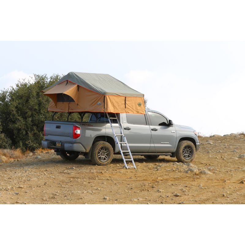 Tuff Stuff Overland Ranger Soft Shell Rooftop Tent (3 Person). Rear view of open tent on vehicle with ladder at campsite