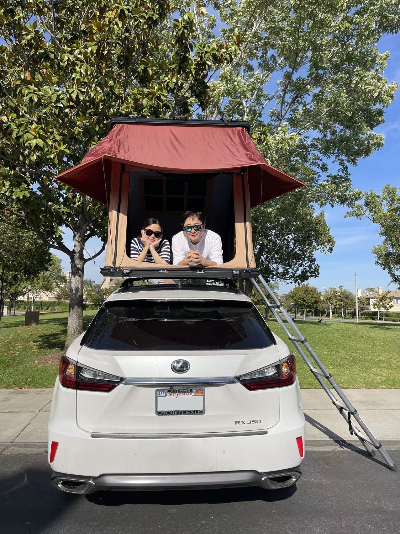 Trustmade Scout MAX Series - Triangular Hard Shell Rooftop Tent assembled on suv with ladder in parking lot with people inside